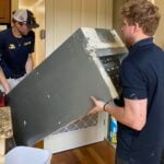 Sheridan’s Trusted HVAC Experts For Over 40 Years 2 Two men moving a heavy appliance